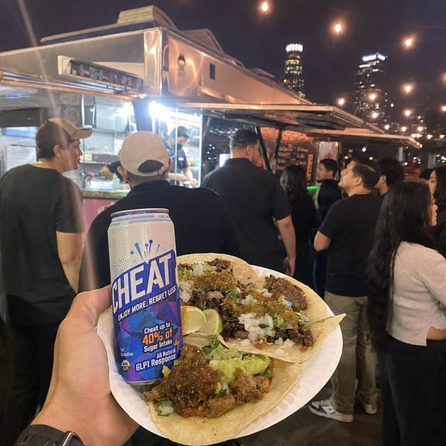 Taco truck at night in Los Angeles, a paper plate of street tacos with lime, string lights, people waiting in line
