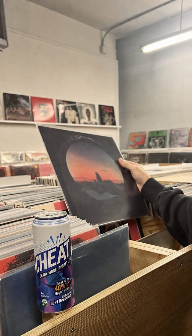 Record shop crate digging, a person holding up a sleeve, stacks of vinyl, fluorescent light
